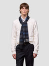 Man wearing a blue and black tartan cashmere scarf on a plain background