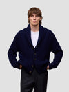 Man wearing a navy blue cashmere cardigan over a white shirt on a light gray background