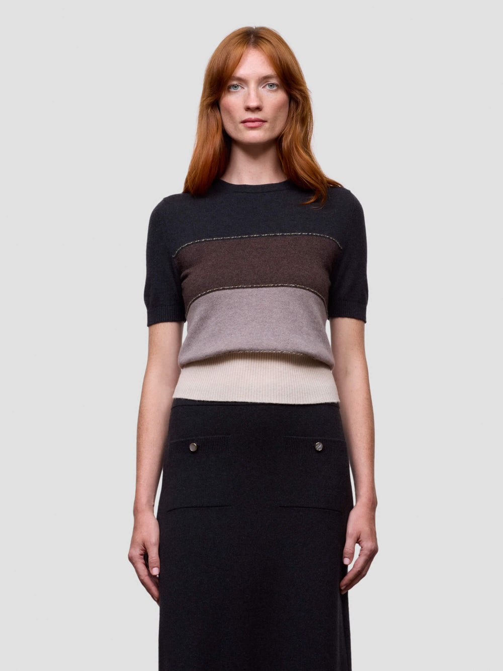 Woman wearing a black, brown, and beige color-blocked cashmere t-shirt on a light gray background