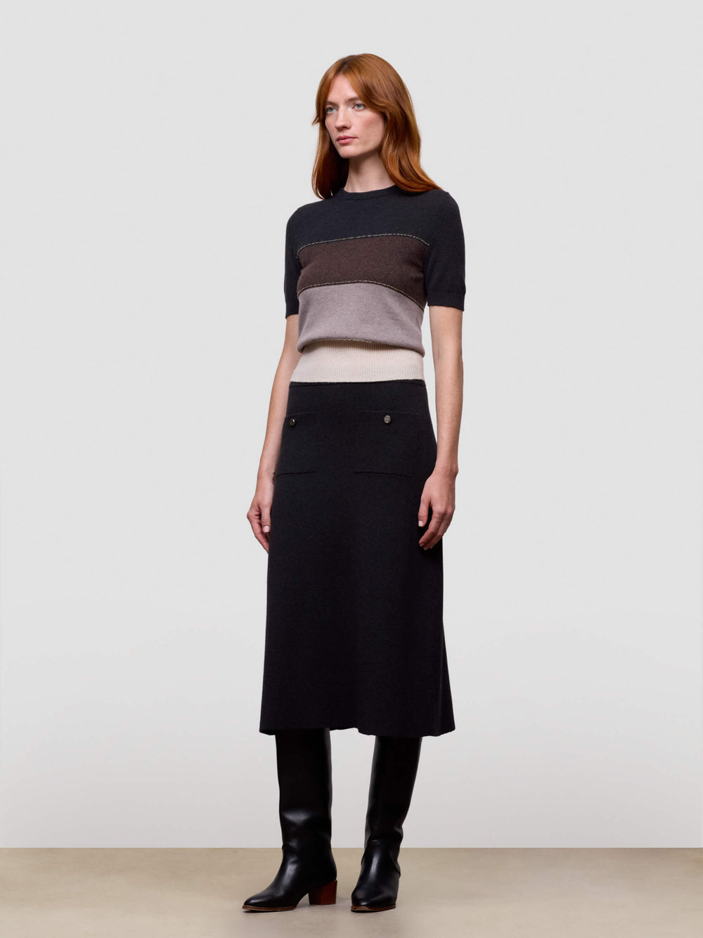 Woman wearing a black, brown, and beige color-blocked cashmere t-shirt on a light gray background
