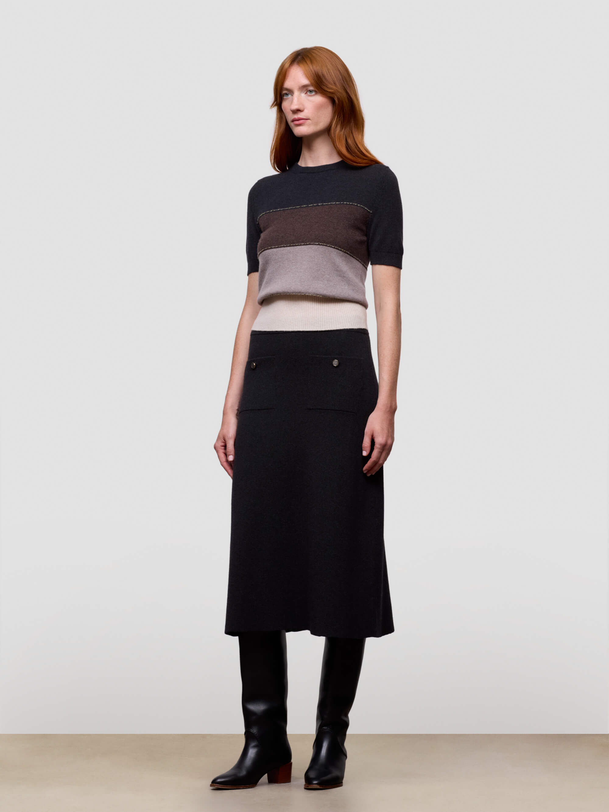Woman wearing a black, brown, and beige color-blocked cashmere t-shirt on a light gray background