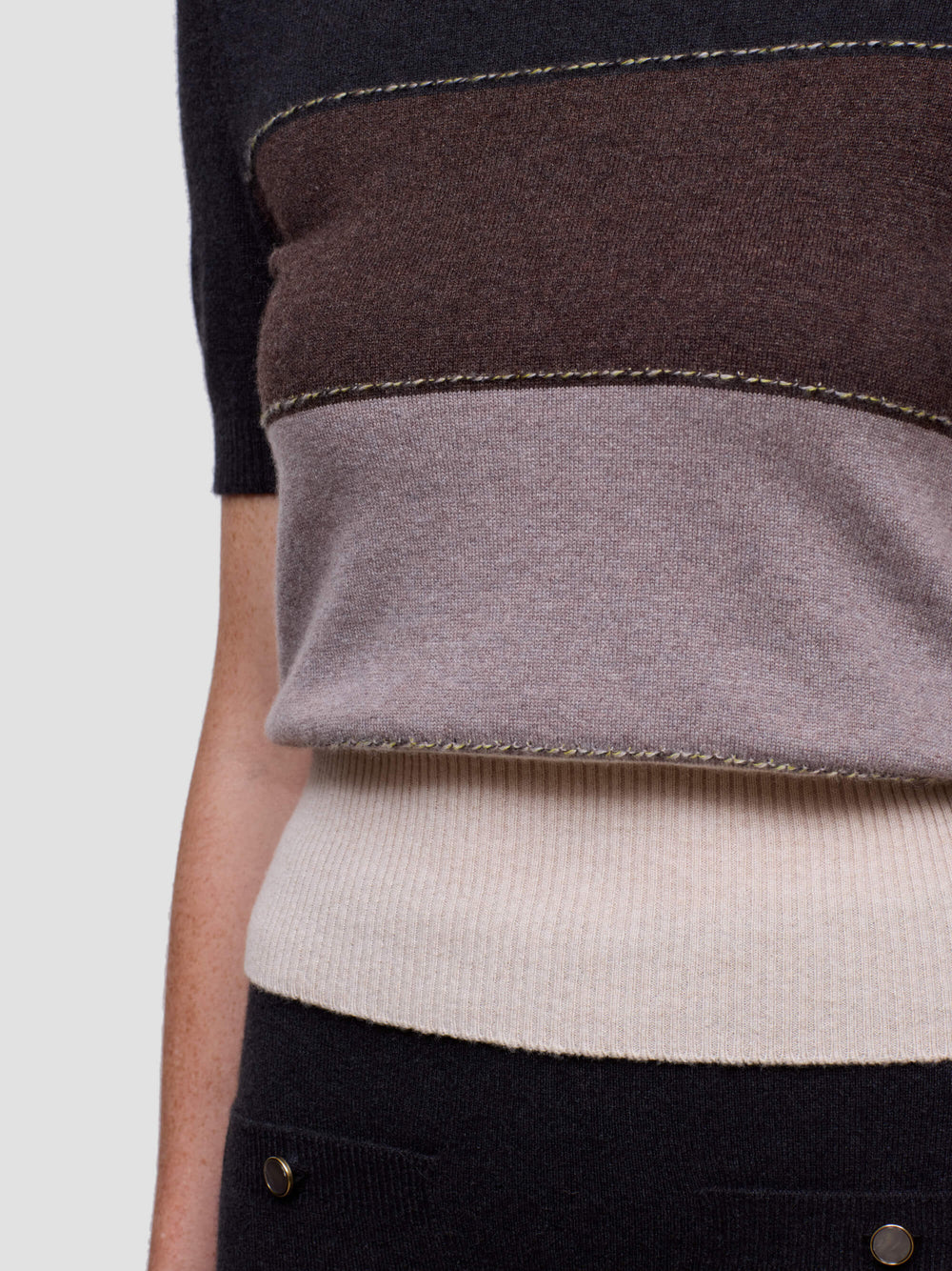 Woman wearing a black, brown, and beige color-blocked cashmere t-shirt on a light gray background