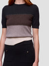 Woman wearing a black, brown, and beige color-blocked cashmere t-shirt on a light gray background