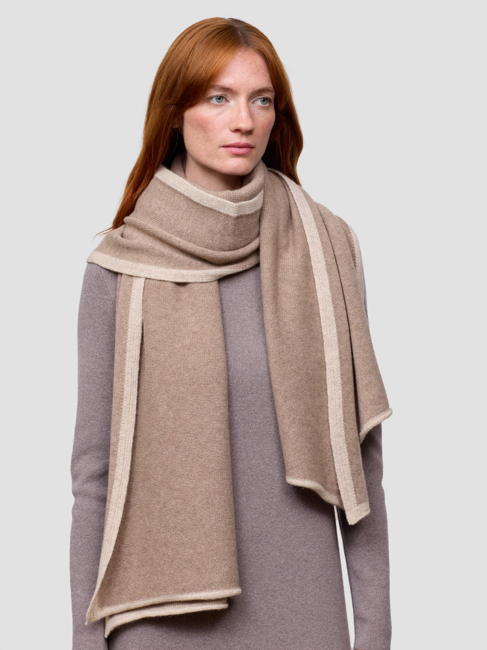 woman wearing a brown cashmere wrap and grey cashmere dress on a grey background