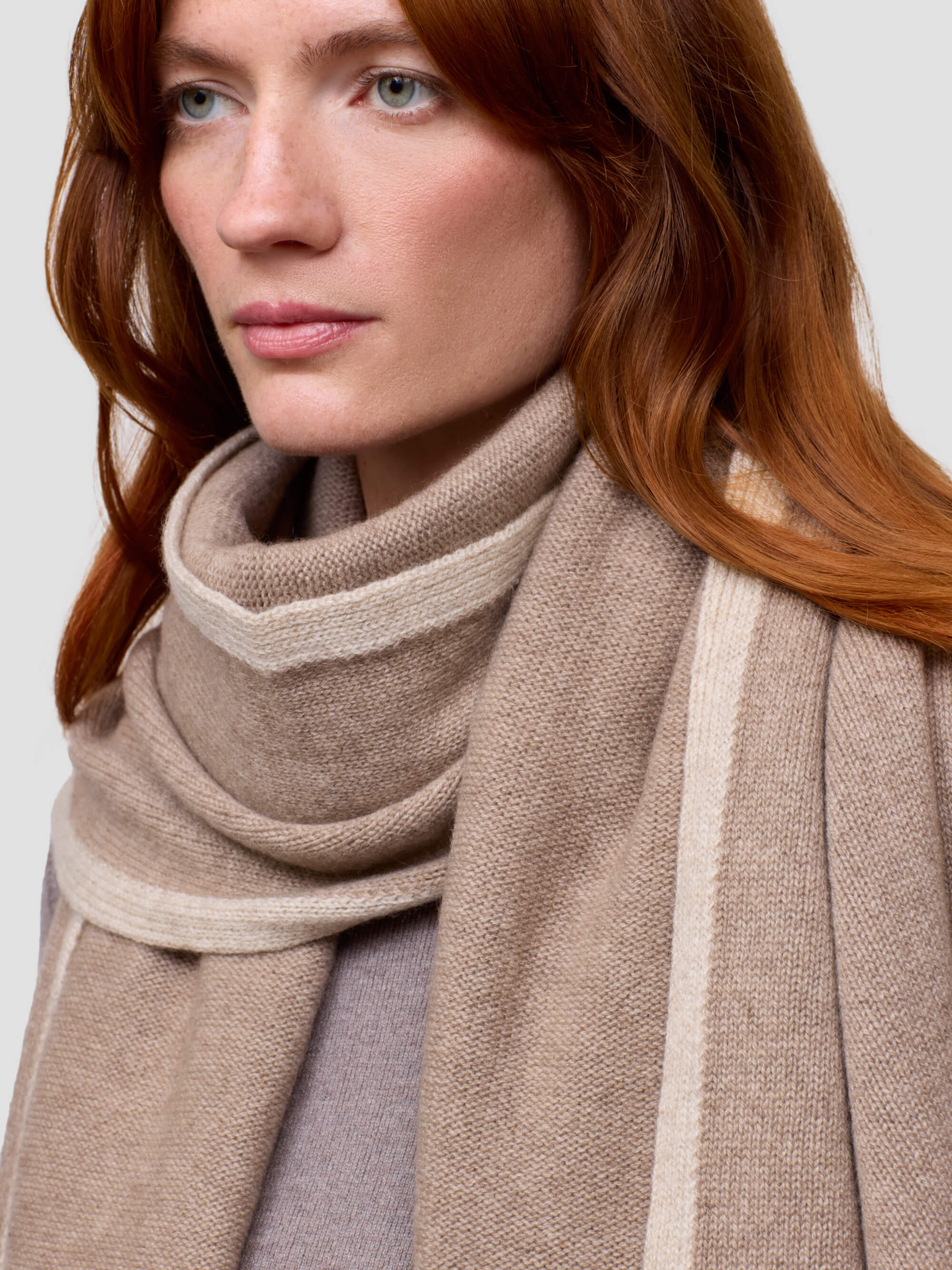 woman wearing a brown cashmere wrap and grey cashmere dress on a grey background