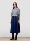 Woman wearing a gray cashmere sweater and blue skirt on a light gray background