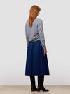 Woman wearing a gray cashmere sweater and blue skirt on a light gray background