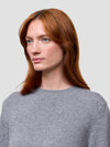 Woman wearing a gray cashmere sweater on a light gray background