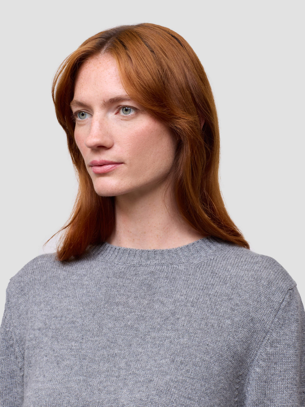 Woman wearing a gray cashmere sweater on a light gray background