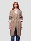 Woman wearing a beige cable knit cashmere cardigan on a light gray background