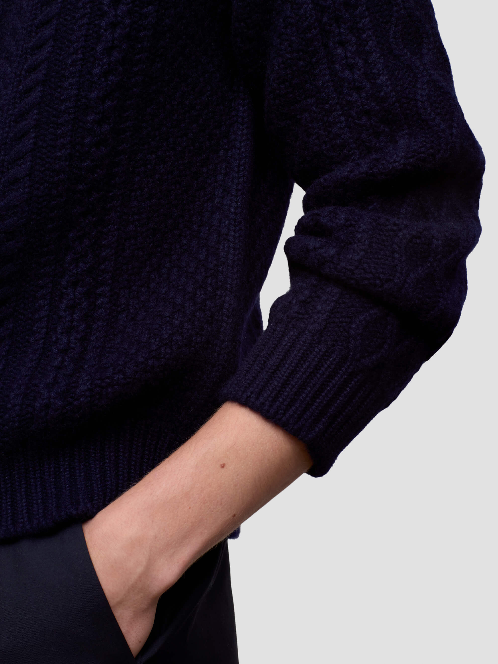 Navy blue knitted sweater worn by a man on a light gray background