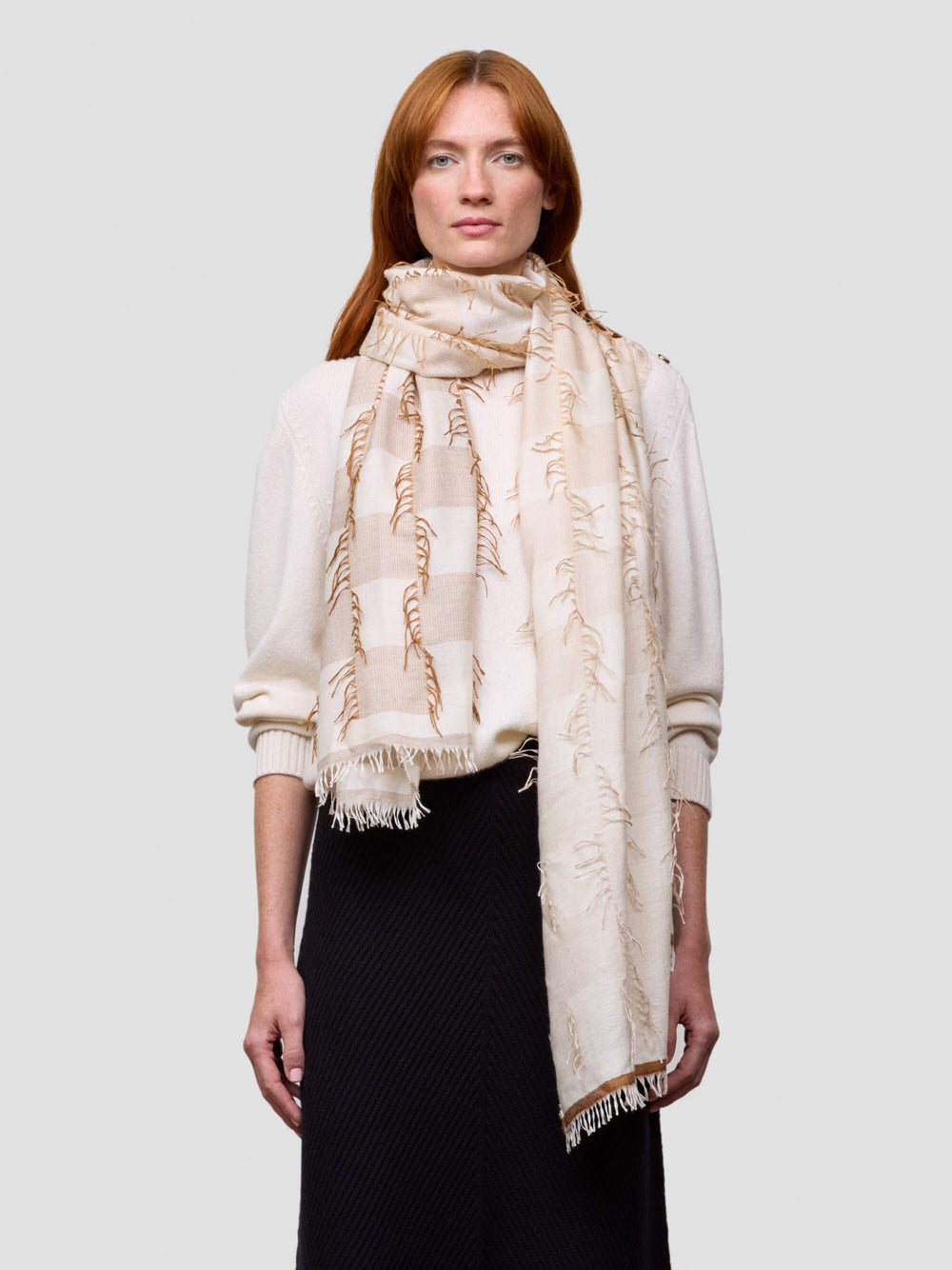 Woman wearing a beige cashmere silk scarf on a plain background
