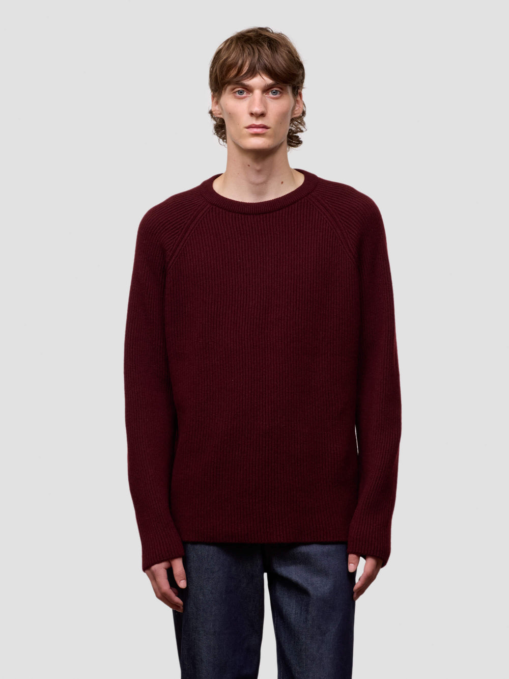 Man wearing a ribbed burgundy cashmere sweater on a light gray background