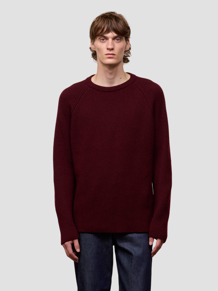 Man wearing a ribbed burgundy cashmere sweater on a light gray background