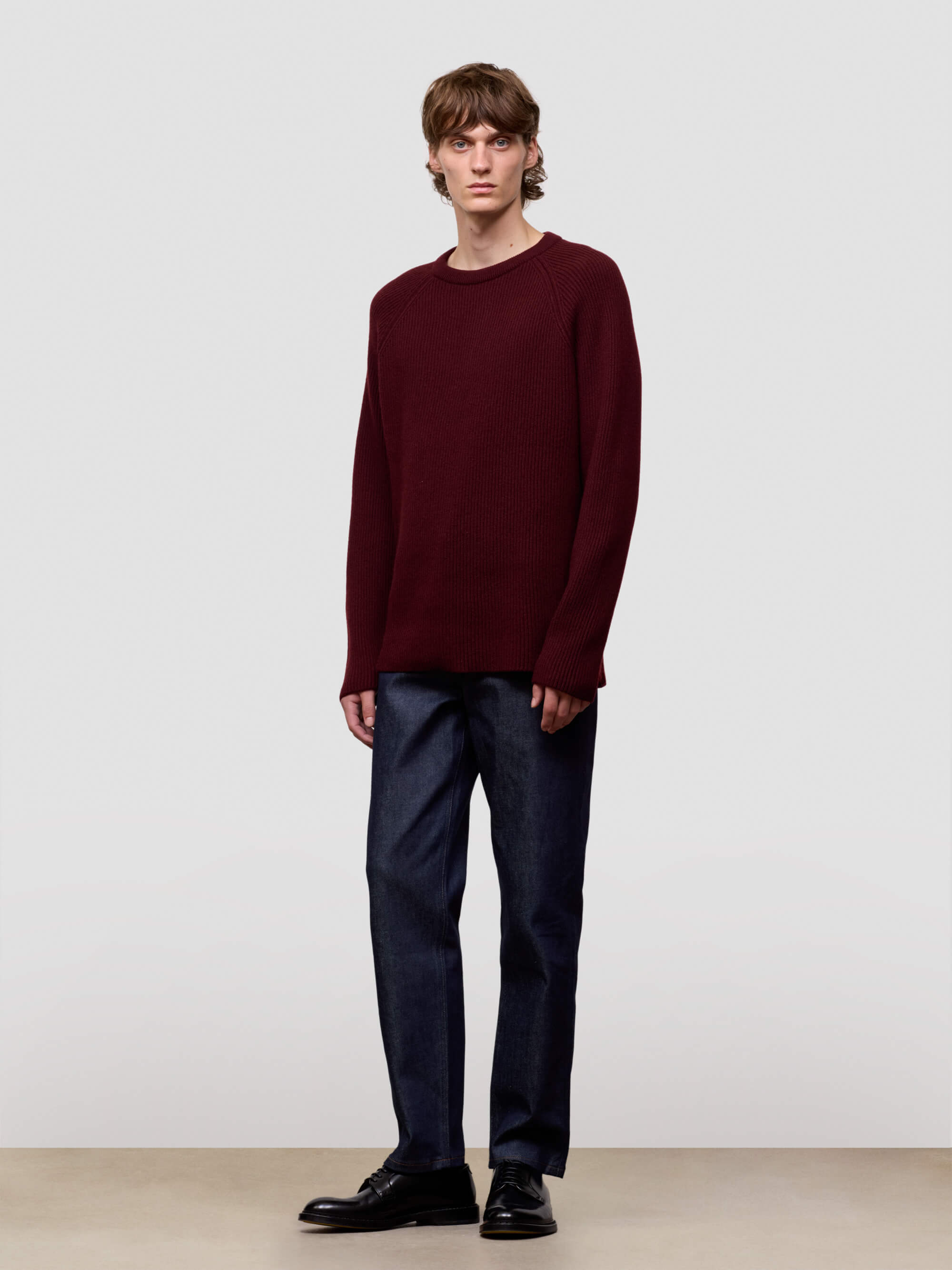 Man wearing a ribbed burgundy cashmere sweater on a light gray background