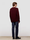 Man wearing a ribbed burgundy cashmere sweater on a light gray background