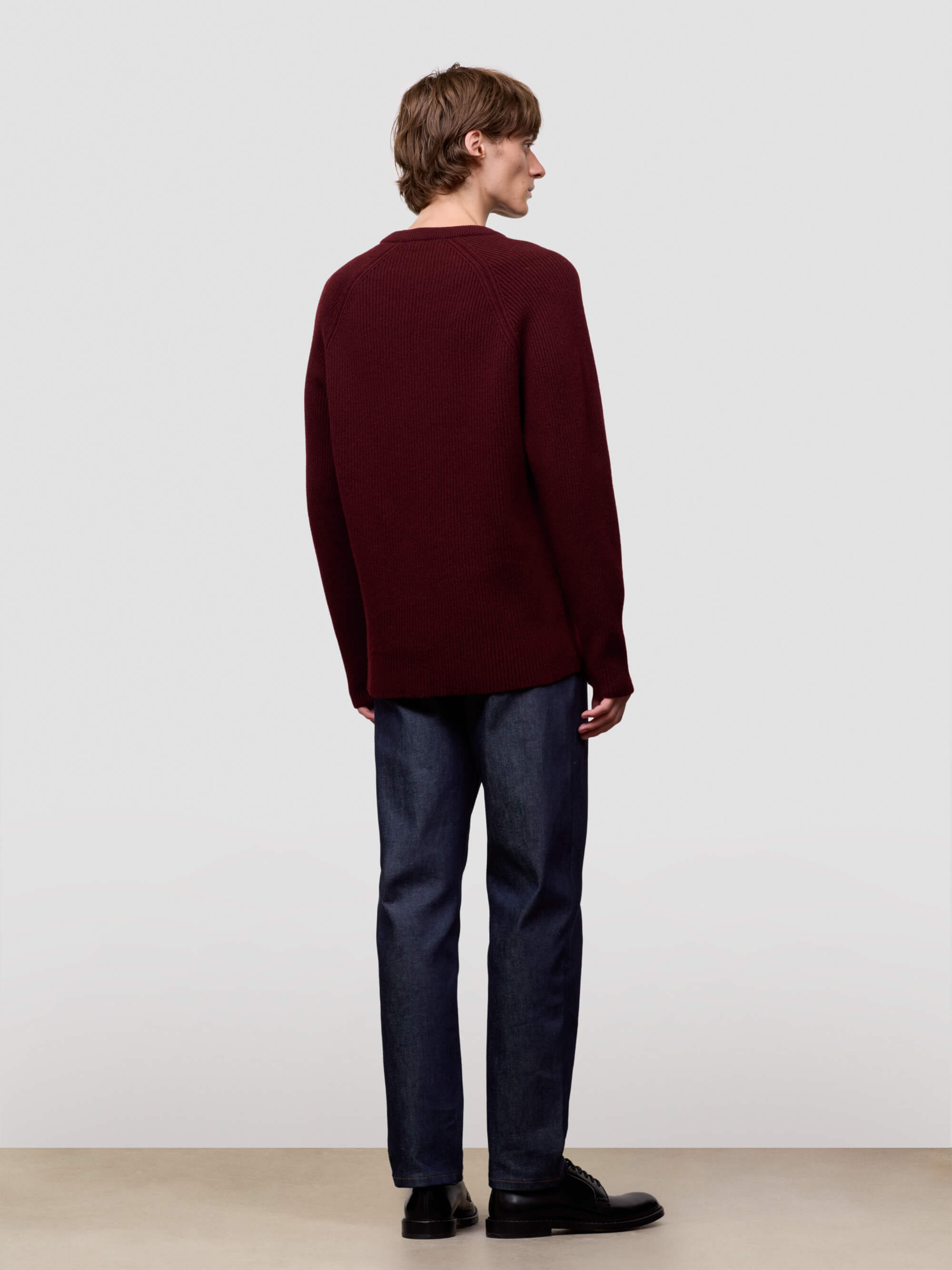 Man wearing a ribbed burgundy cashmere sweater on a light gray background