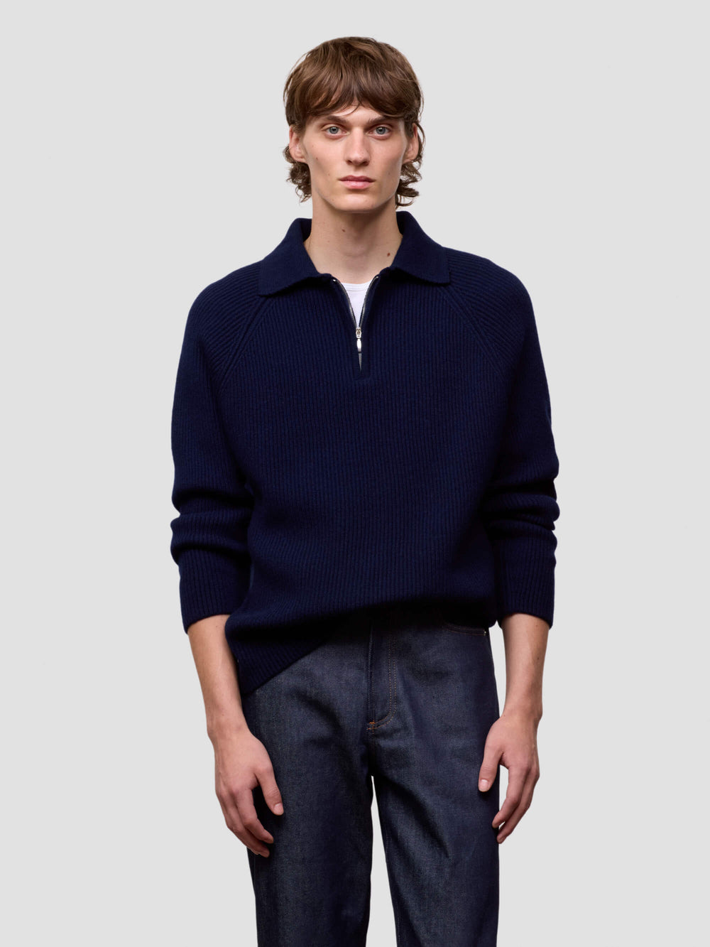 man wearing a navy blue cashmere zip sweater on a light gray background