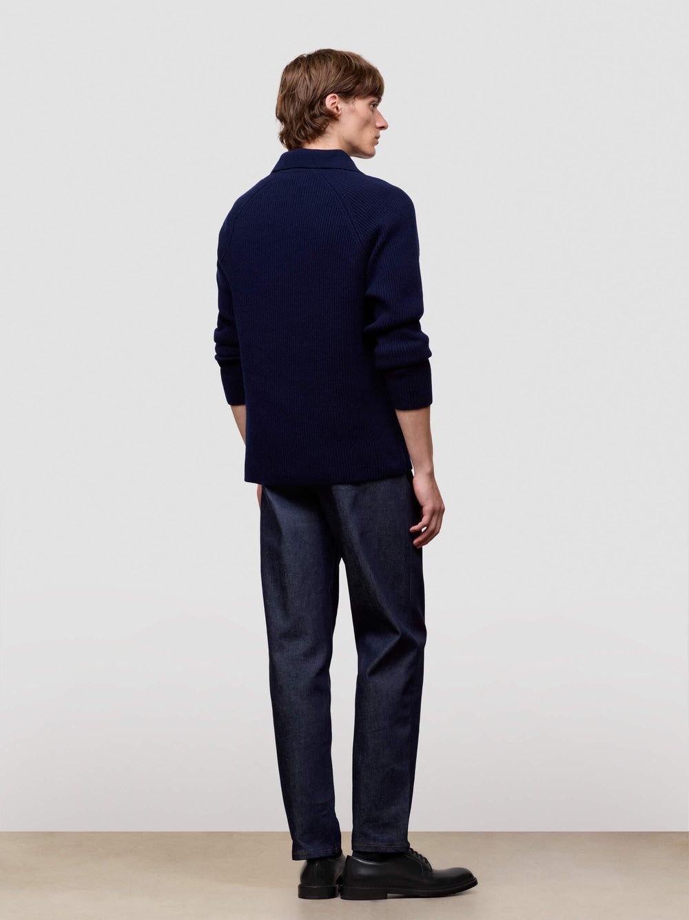 man wearing a navy blue cashmere zip sweater on a light gray background