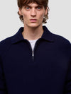 man wearing a navy blue cashmere zip sweater on a light gray background