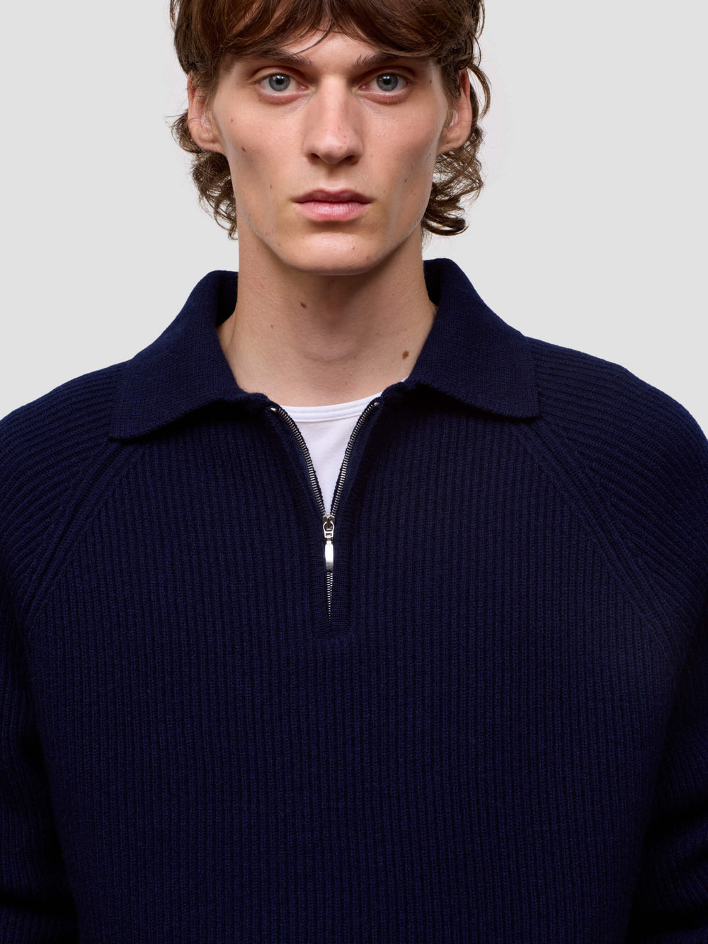 man wearing a navy blue cashmere zip sweater on a light gray background