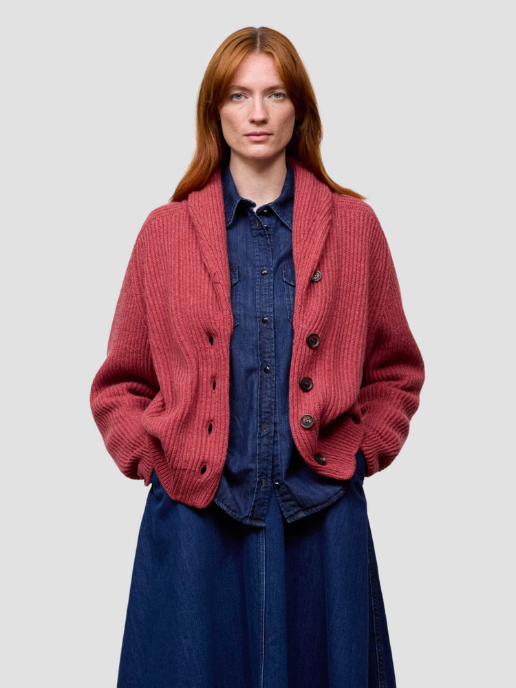 Woman wearing a red cashmere cardigan over a blue dress on a light gray background
