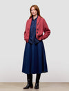 Woman wearing a red cashmere cardigan, blue dress, and black boots on a white background