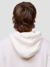 man wearing a white cashmere hoodie on a light gray background