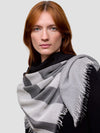 Woman wearing a gray and white patterned scarf on a plain background