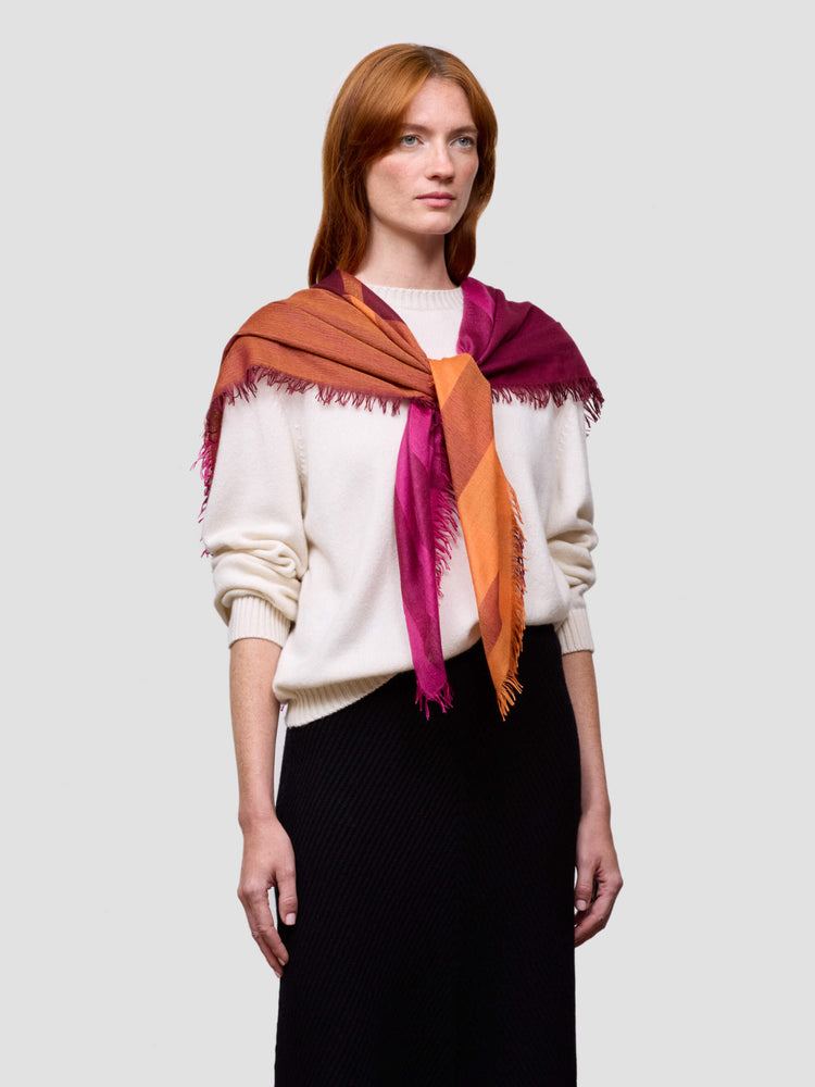 Woman wearing a pink and orange cashmere silk scarf on a plain background