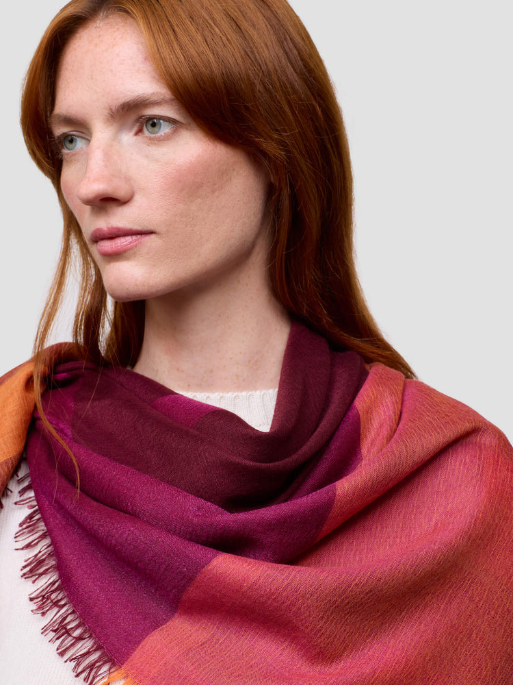 Woman wearing a pink and orange scarf with a neutral background
