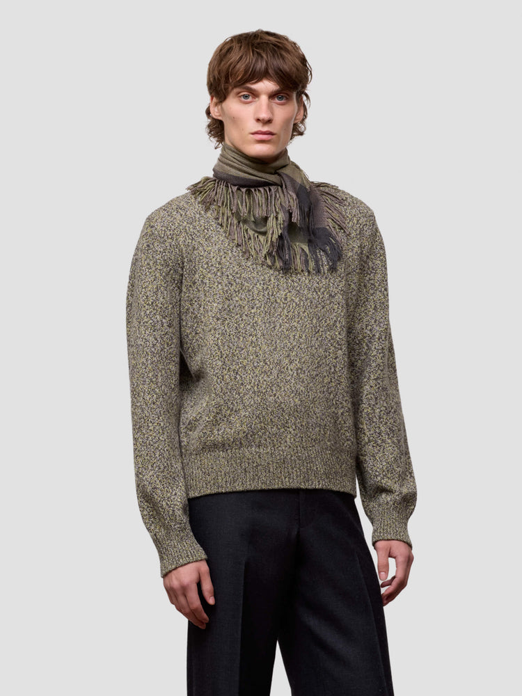 Man wearing a green cashmere scarf and patterned cashmere sweater against a light gray background