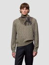 Man wearing a green cashmere scarf and patterned cashmere sweater against a light gray background