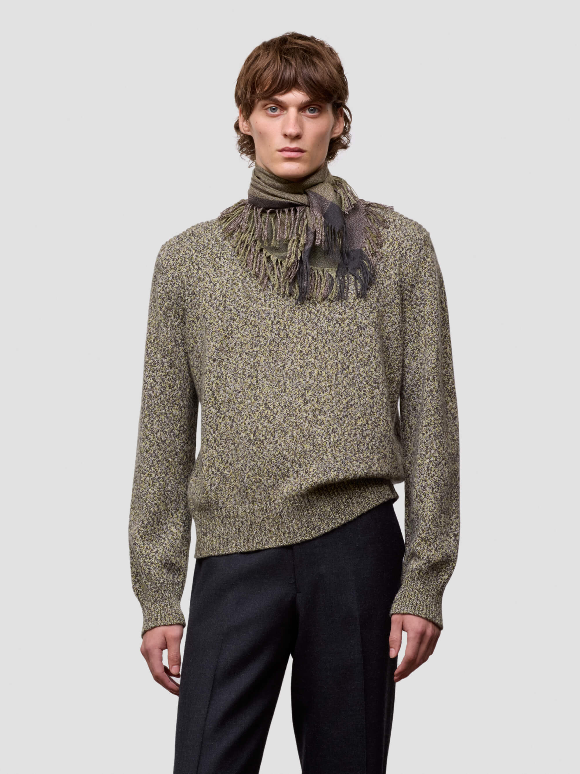 Man wearing a green cashmere scarf and patterned cashmere sweater against a light gray background