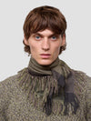 Man wearing a green cashmere scarf and patterned cashmere sweater against a light gray background