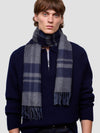 Man wearing a dark blue cashmere sweater and plaid cashmere scarf against a light gray background
