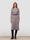 Woman wearing a grey long-sleeve cashmere dress with a belt against a plain background