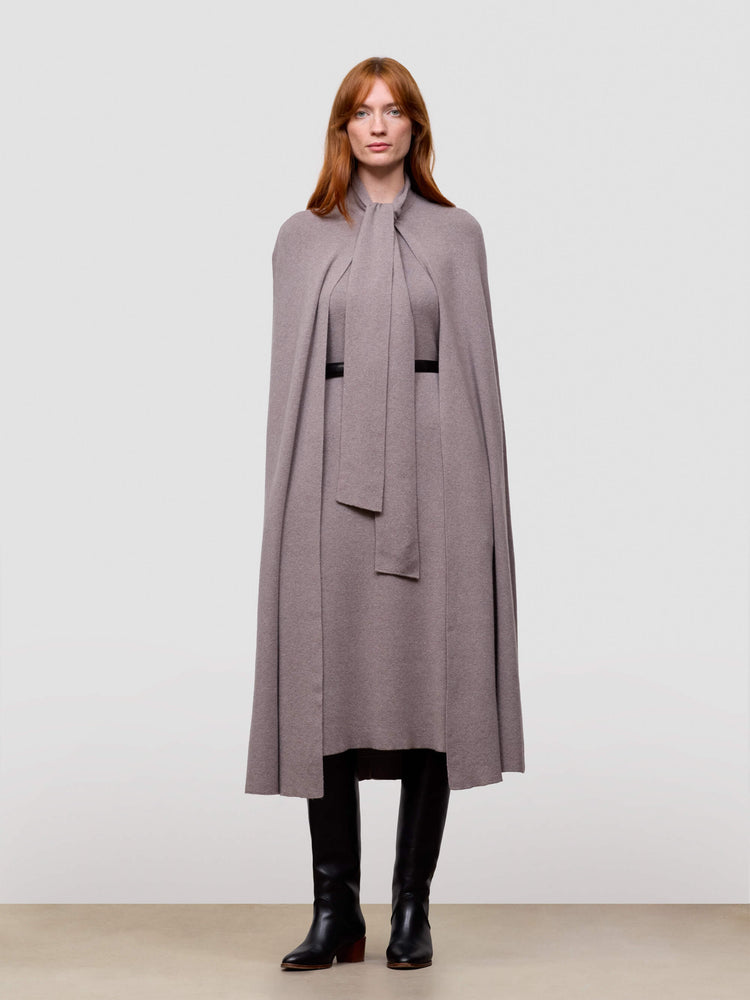 Woman wearing a long gray cashmere cape with a plain background