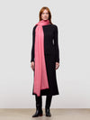 Woman wearing a black cashmere dress and pink cashmere scarf on a white background