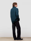 Man wearing a green cashmere cardigan over a white shirt on a light gray background