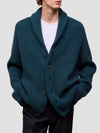 Man wearing a green cashmere cardigan over a white shirt on a light gray background