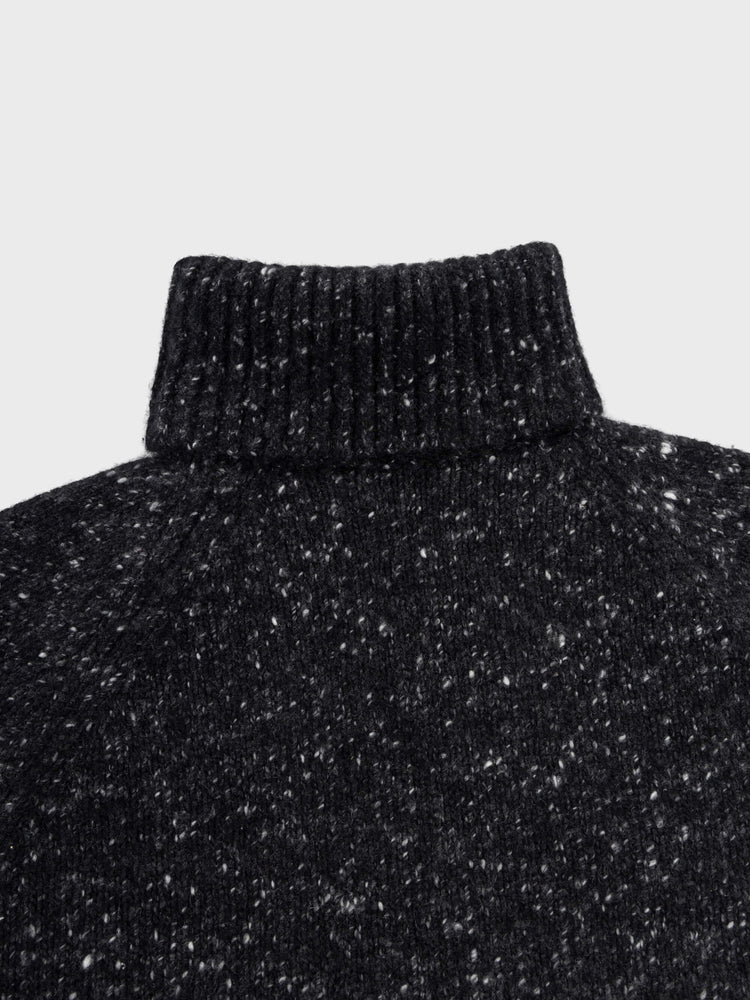 black chunky cashmere roll collar sweater with white speckles detail on a grey background