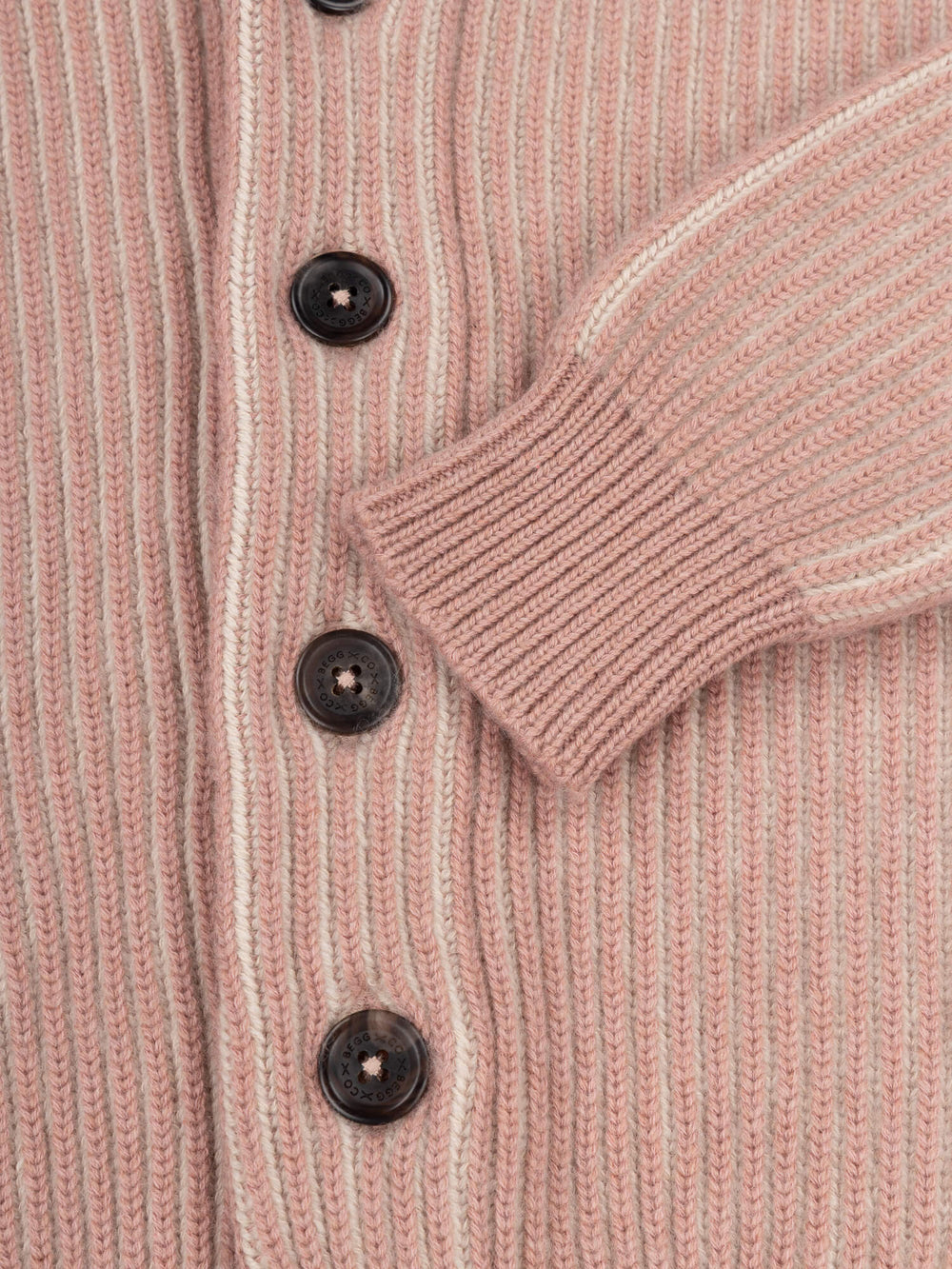 cuff and button close up on a pink ribbed shawl collar cardigan on a grey background