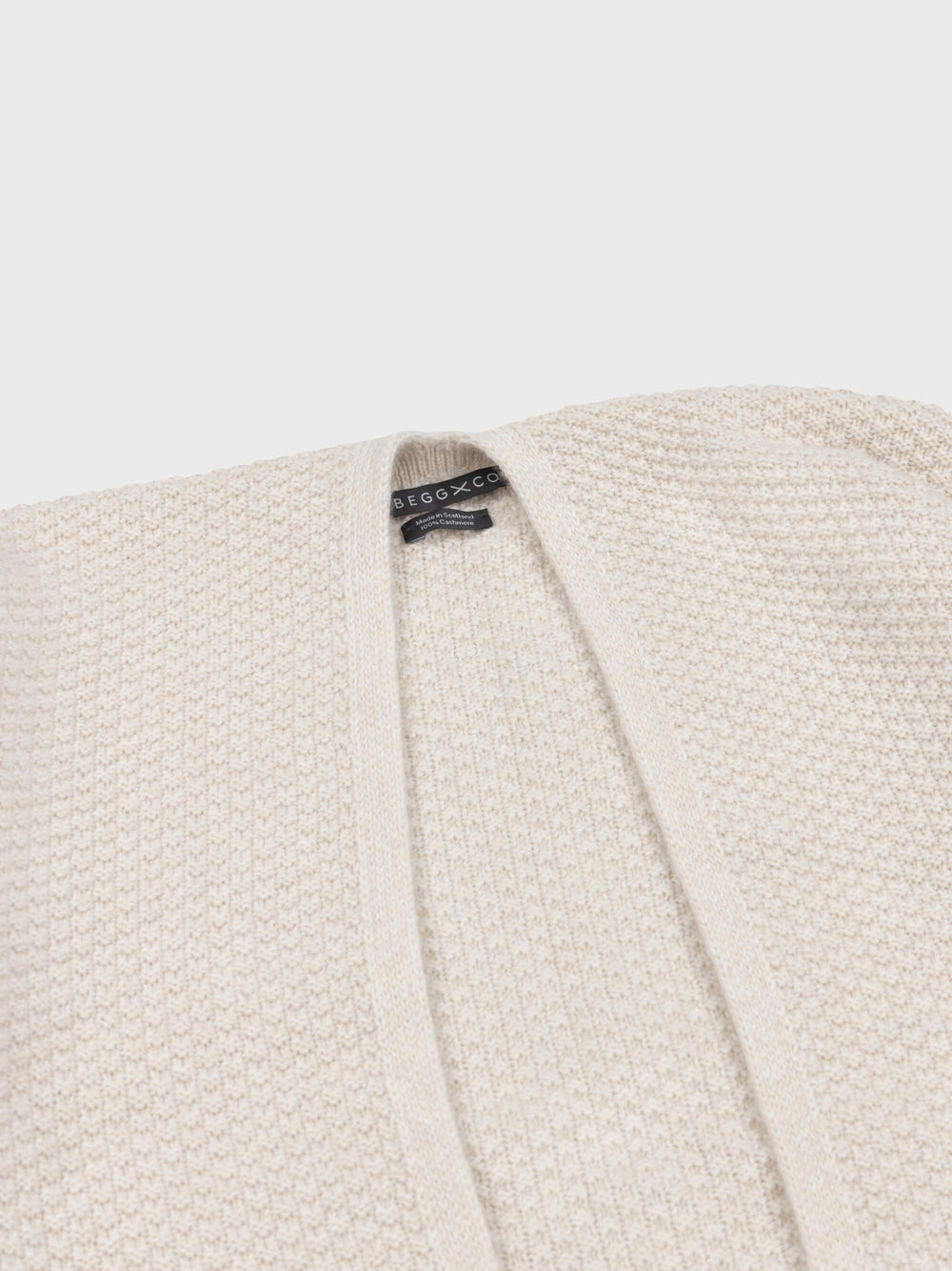 beige cashmere poncho neck detail on a grey background