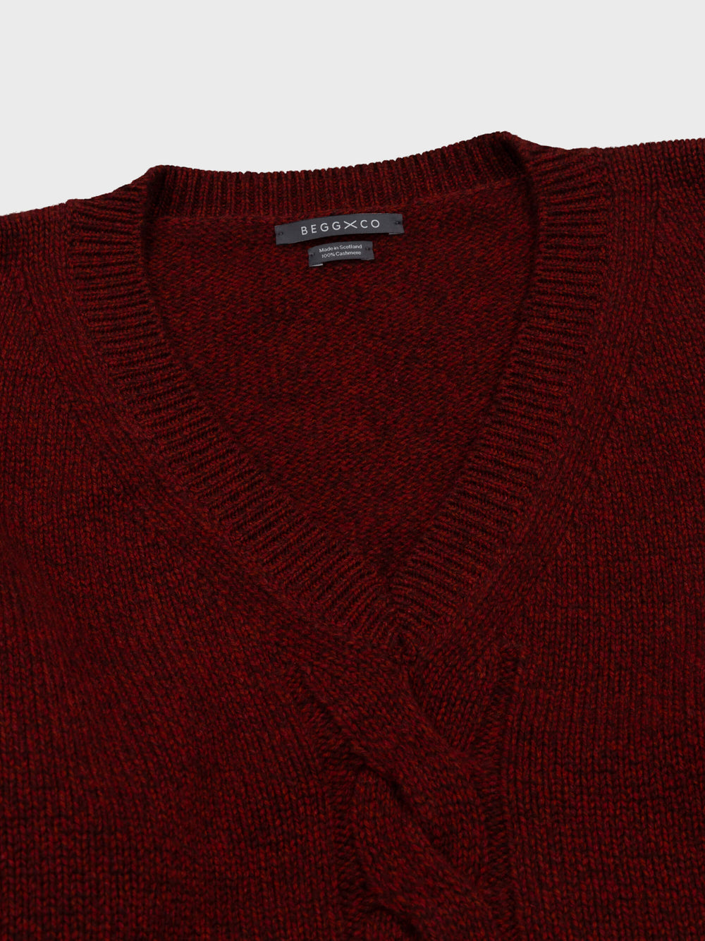 red cashmere v-neck sweater detail with cable knit detail down middle on grey background