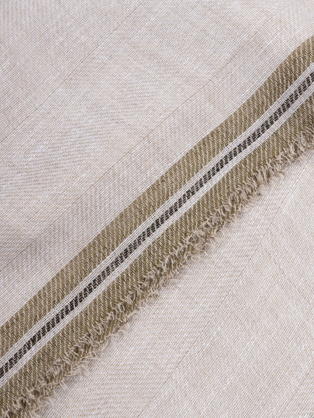 close up of a beige scarf with dark green edges