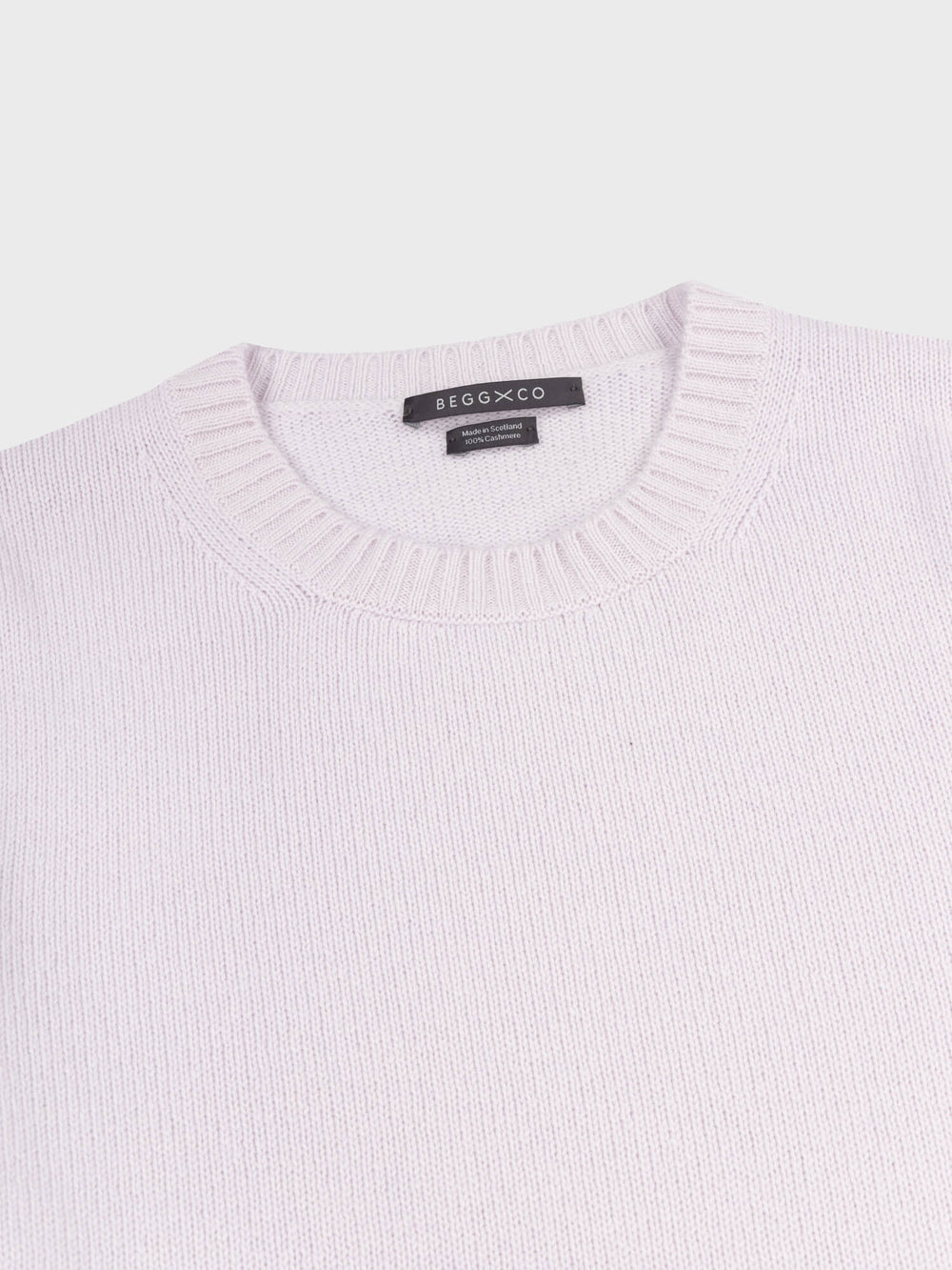 crewneck detail of a light purple cashmere sweater on a grey background
