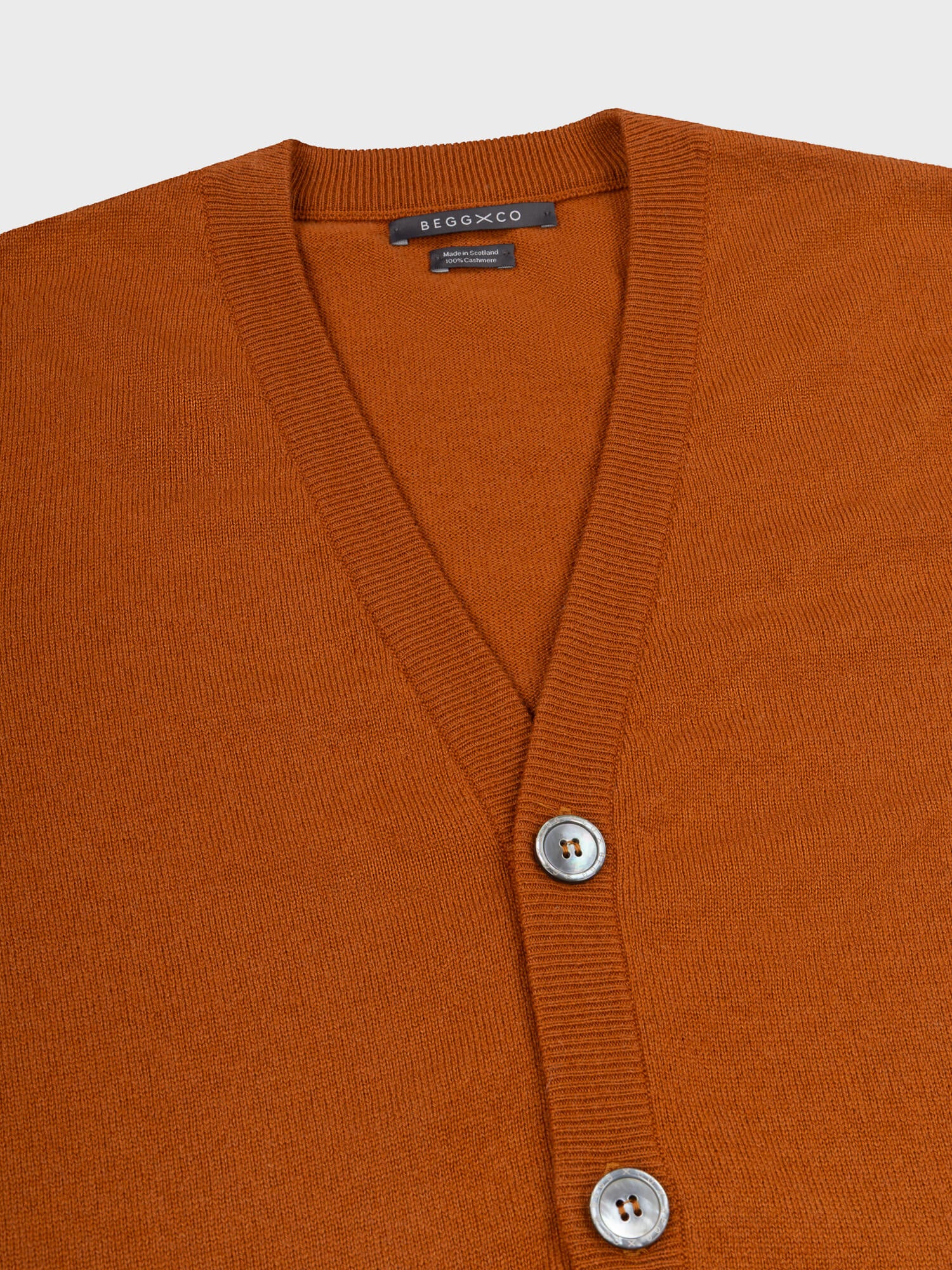 close up of a button up brown cashmere cardigan on a grey background