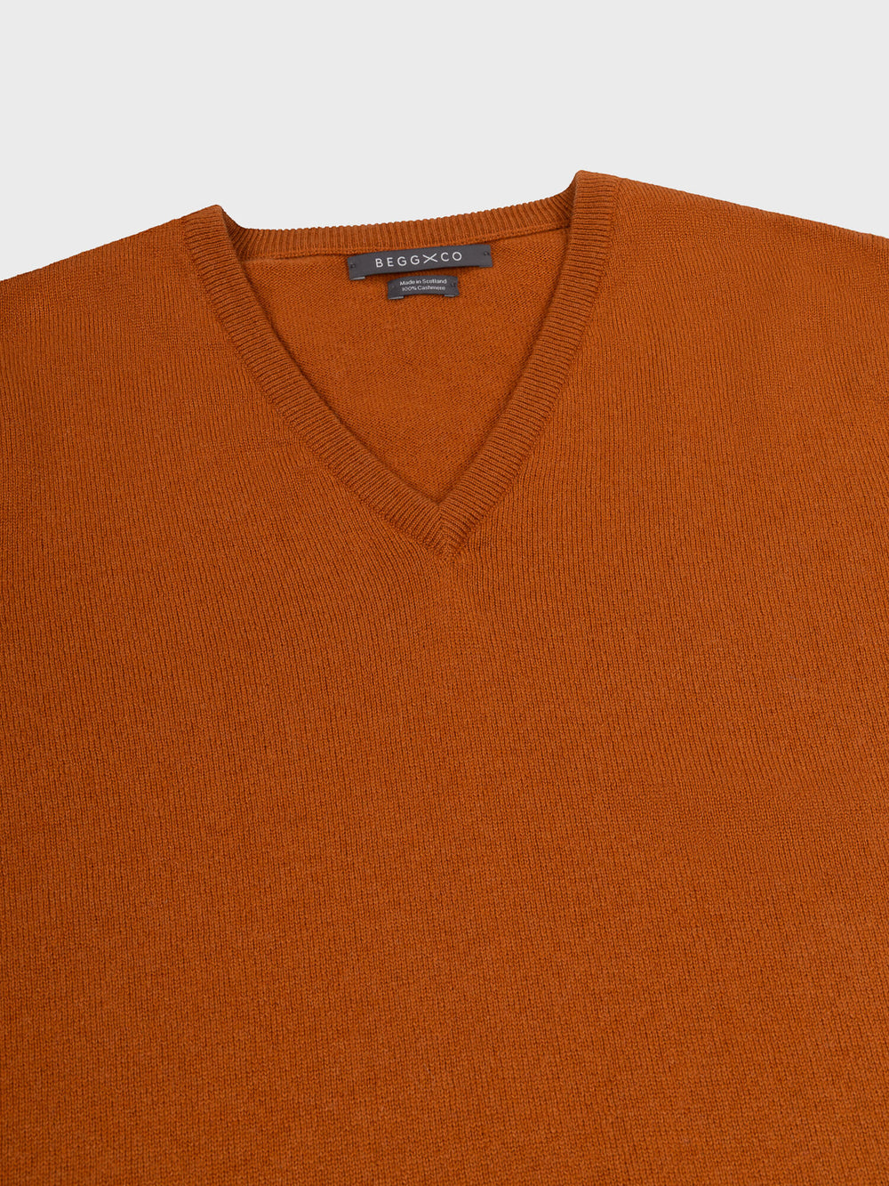 neck detail of a brown cashmere v-neck sweater on a grey background