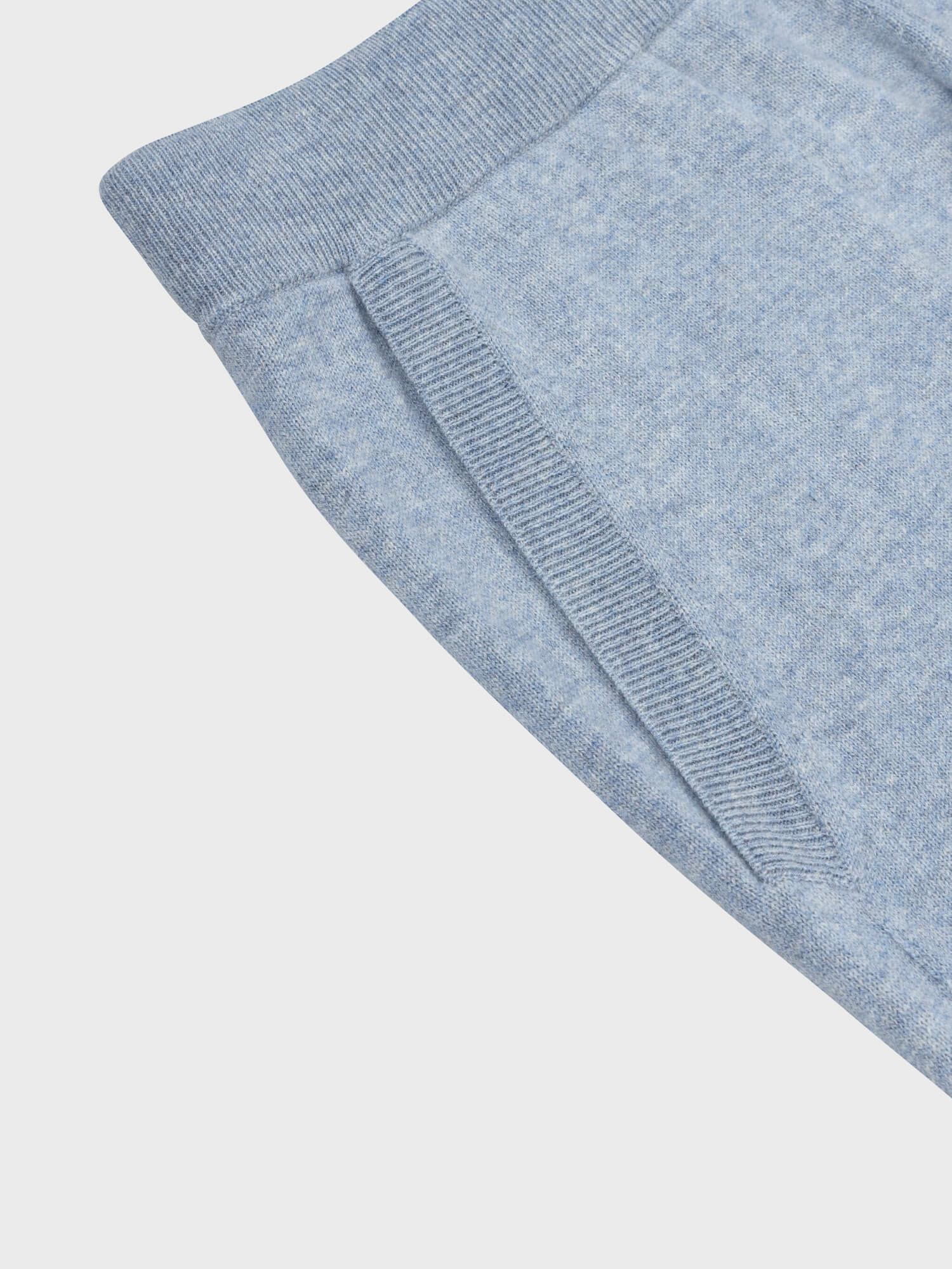 pocket detail of faded blue cashmere sweatpants on a grey background